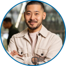 Retrato profissional em close-up de homem (asiático) sorrindo, com barba e camisa bege, ideal para a seção 'Nossa Equipe' de consultoria.
